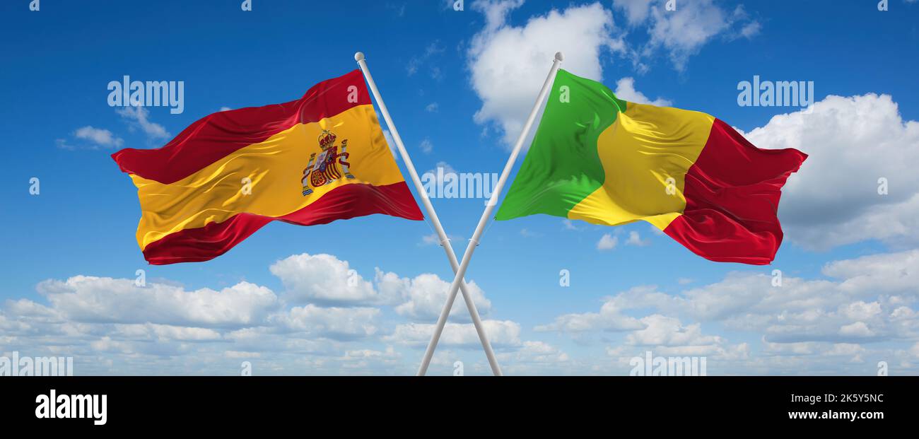 two crossed flags Mali and spain waving in wind at cloudy sky. Concept ...