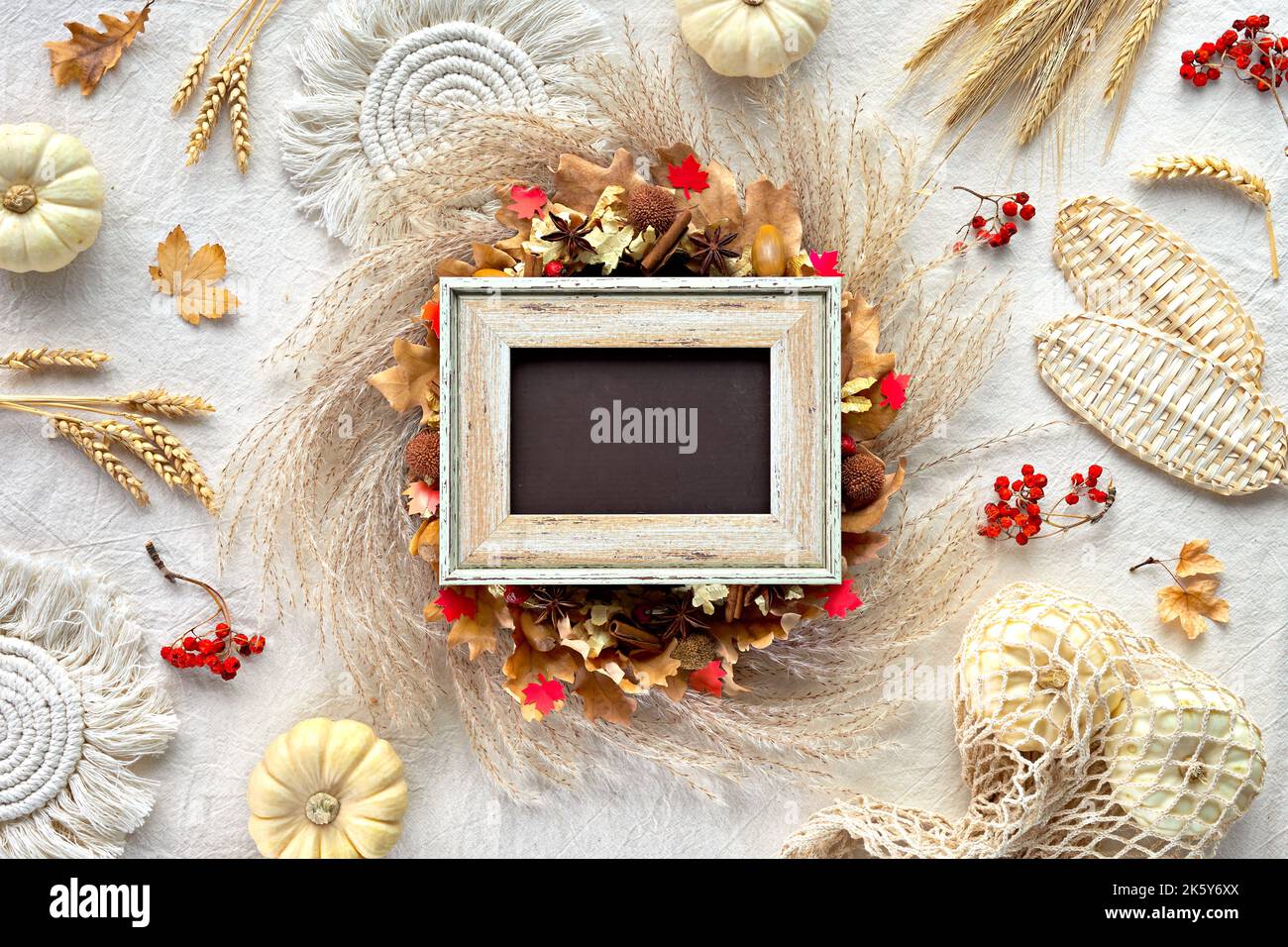 Off white textile background with natural Fall decorations. Text Autumn Blessings on letter board. Flat lay, top view. Pumpkins in net bag, dry leaves Stock Photo