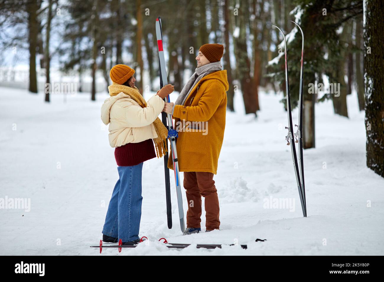 Full length portrait of young couple skiing in winter forest while enjoying holiday vacation, copy space Stock Photo