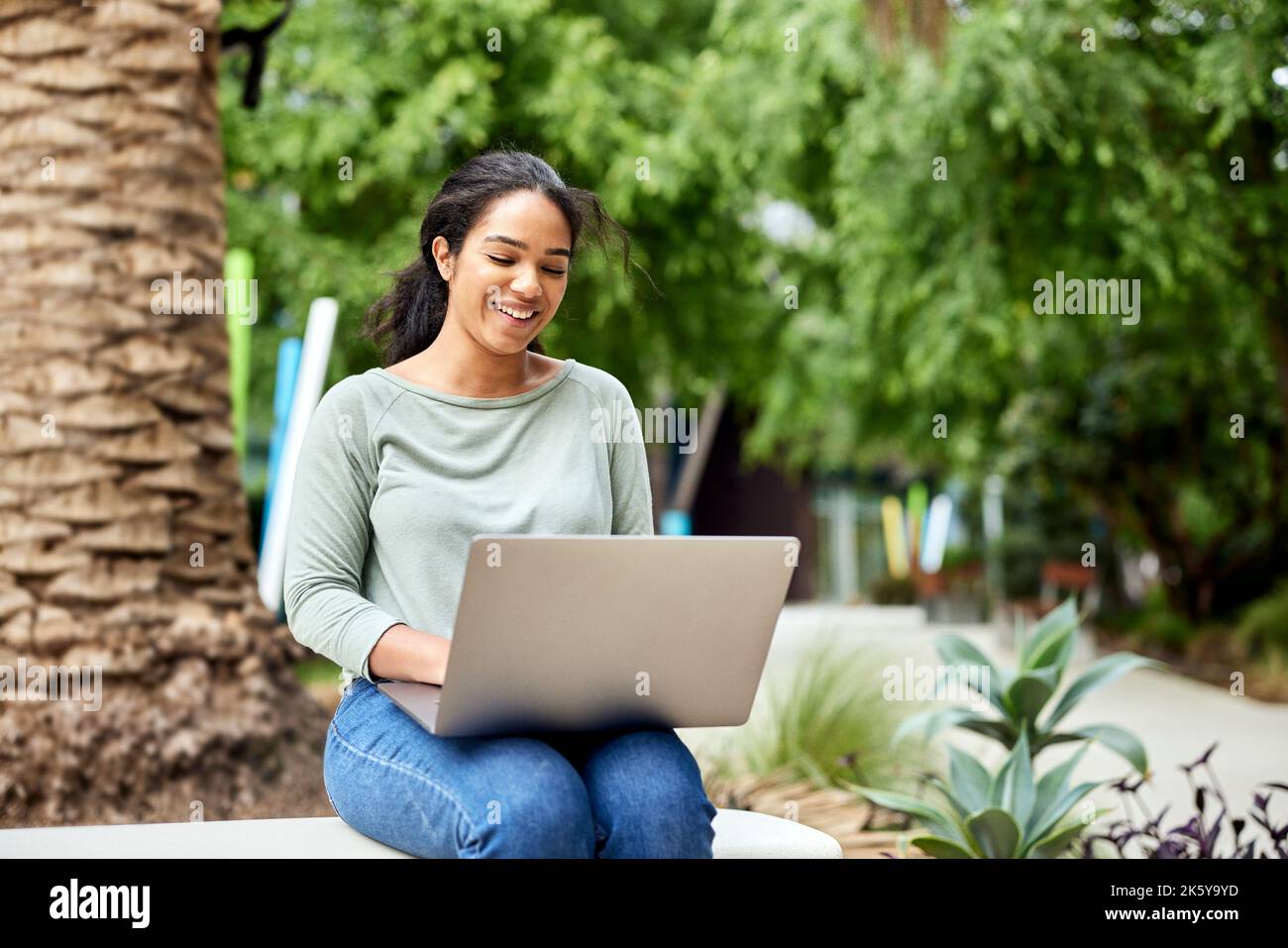 Smiling female freelancer using laptop while sitting on bench Stock Photo