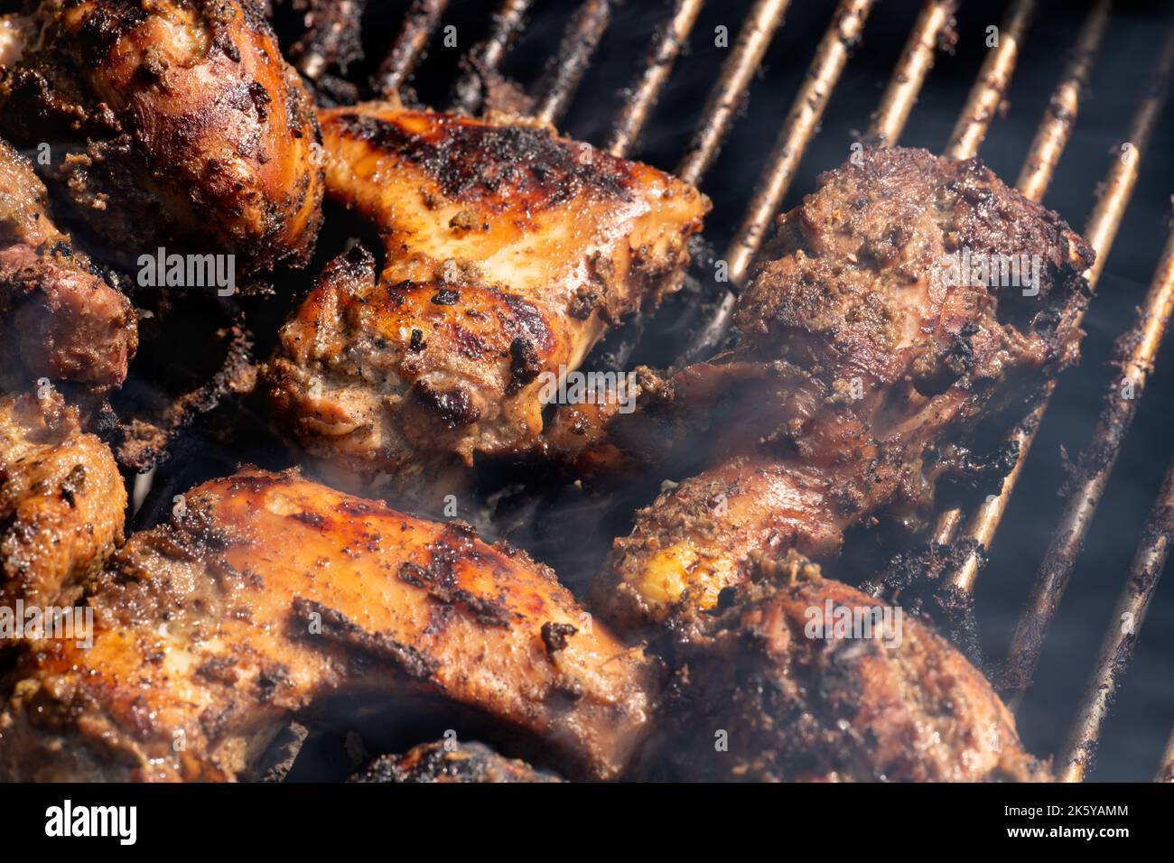 Grilling traditional Jamaican spicy jerk chicken with over charcoal fire Stock Photo Alamy
