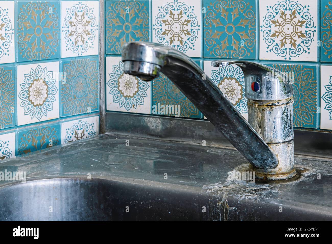 Old rusty sink faucet in kitchen. Rust streaks, calcium scale, hard