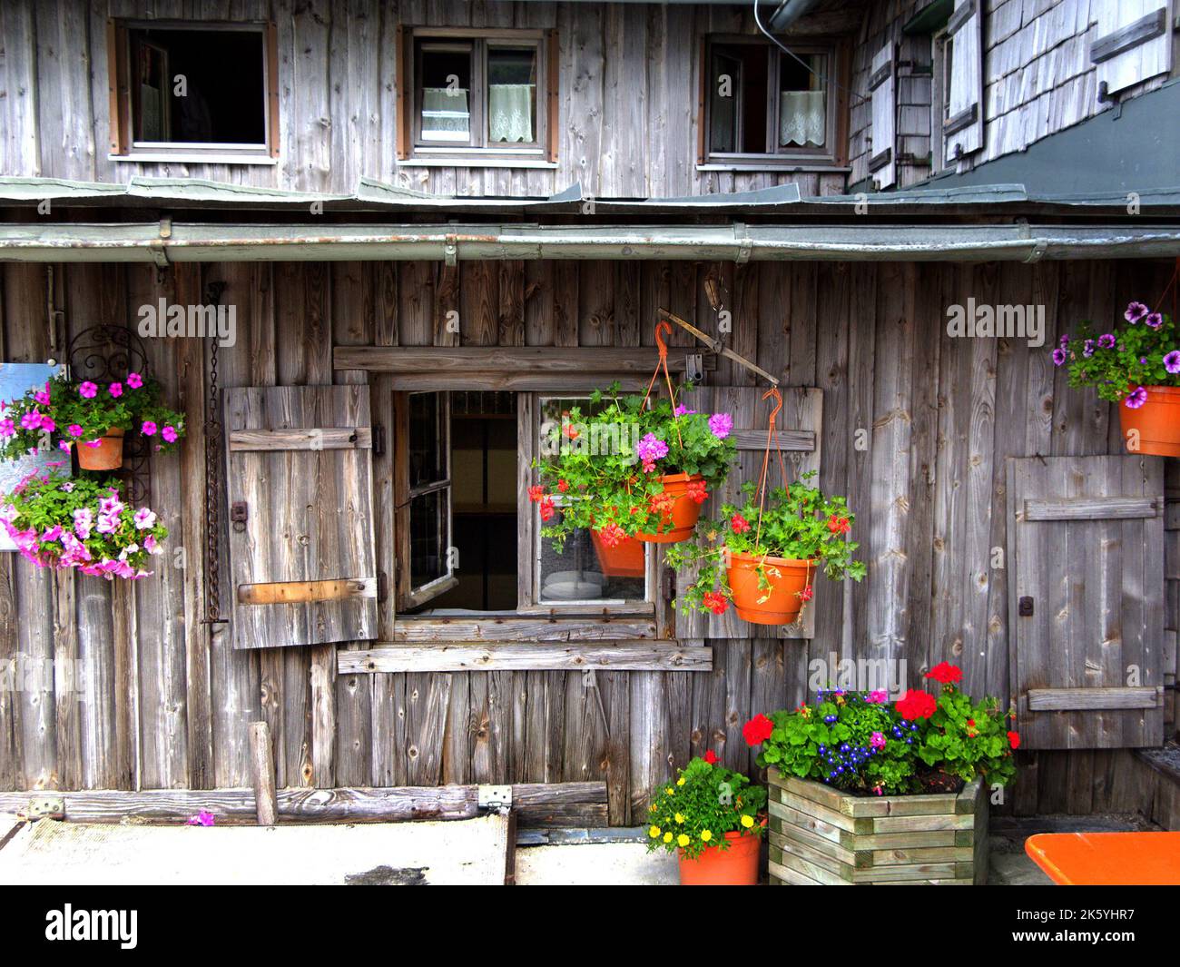 Detail of alpine wooden house, windows and flowerpots, Chiemgau, Bavaria, Germany. Detail eines alpinen Holzhauses, Fenster und Blumenschmuck, Stock Photo