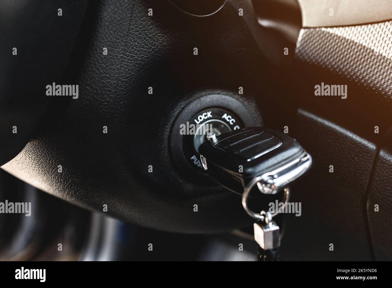 Key in car ignition lock under the steering wheel in a black interior