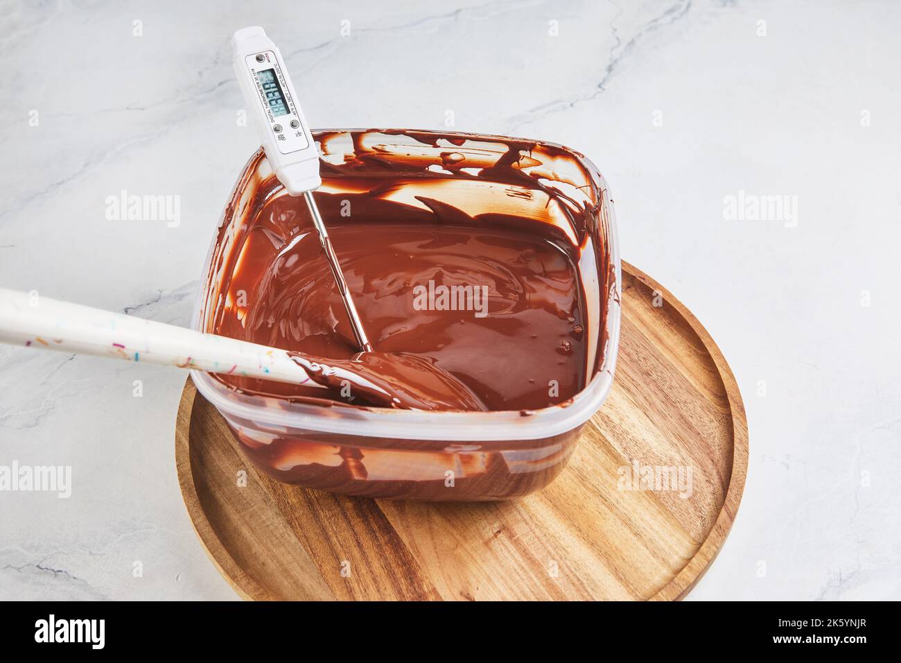 Melted chocolate is measured with thermometer to check the temperature before being poured into