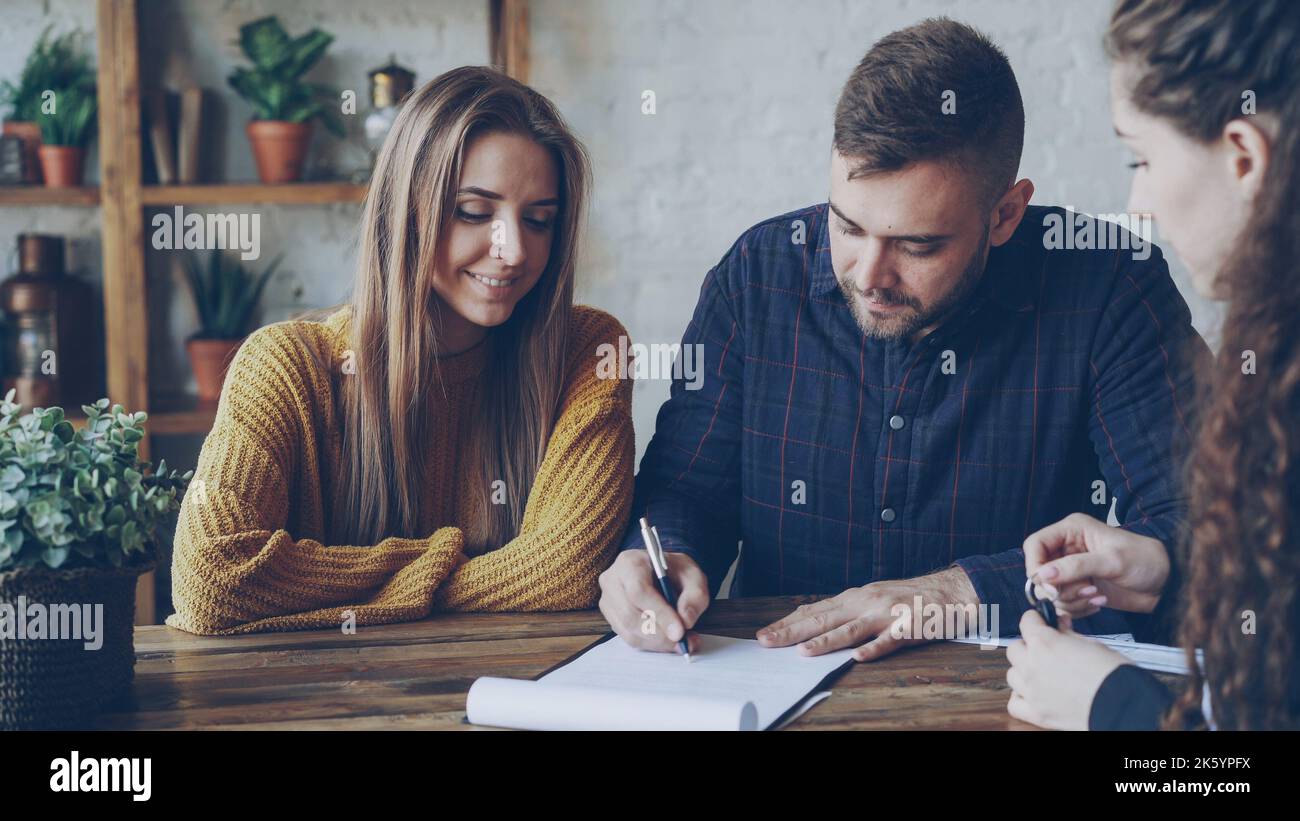 Female realtor is reading purchase and sell agreement to young couple ...
