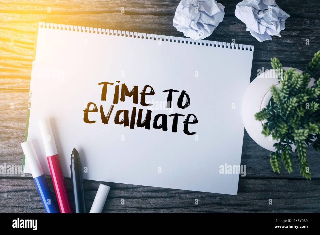 Time to evaluate word with Notepad and green plant on wooden background ...