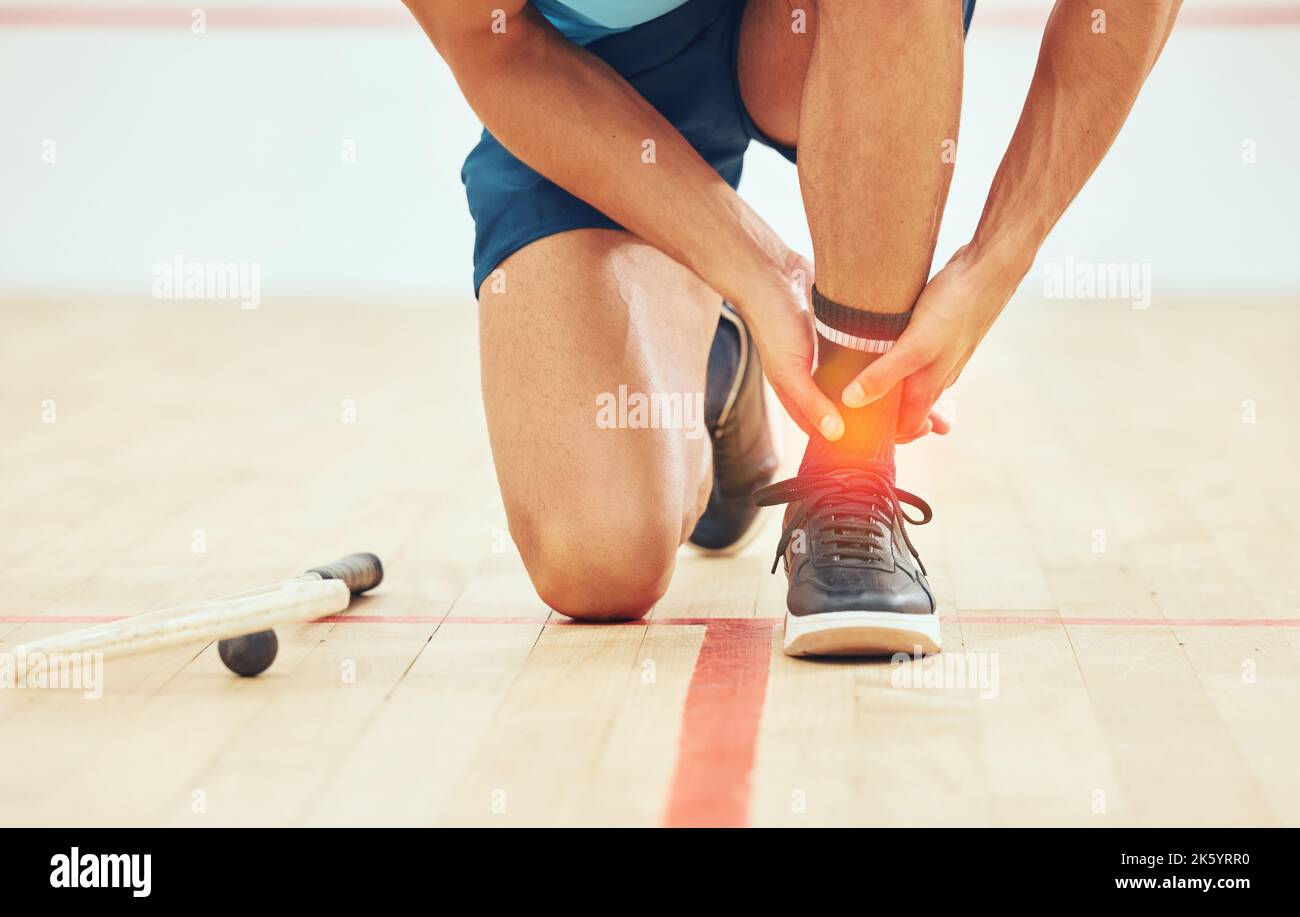 Unknown squash player suffering from ankle sprain during court game. Fit active mixed race athlete kneeling and feeling pain in achilles tendon. Cgi Stock Photo