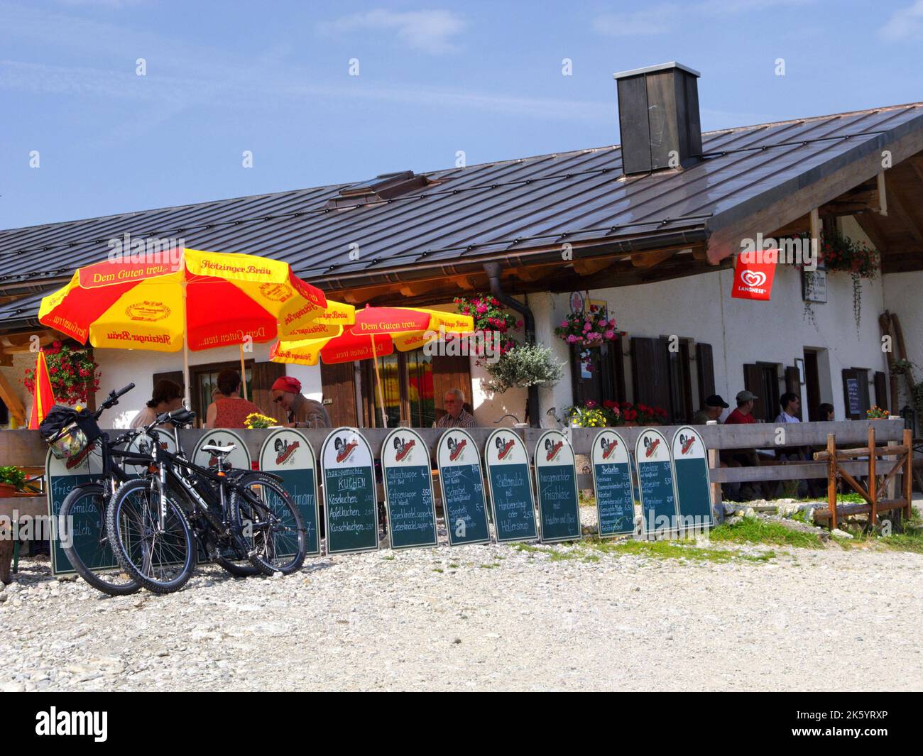 Alpine restaurant 'Gori Alm' with guests, terrace and sun umbrellas, Kampenwand mountain, Chiemgau, Bavaria, Germany. Berggasthof 'Gori Alm', Terrasse Stock Photo