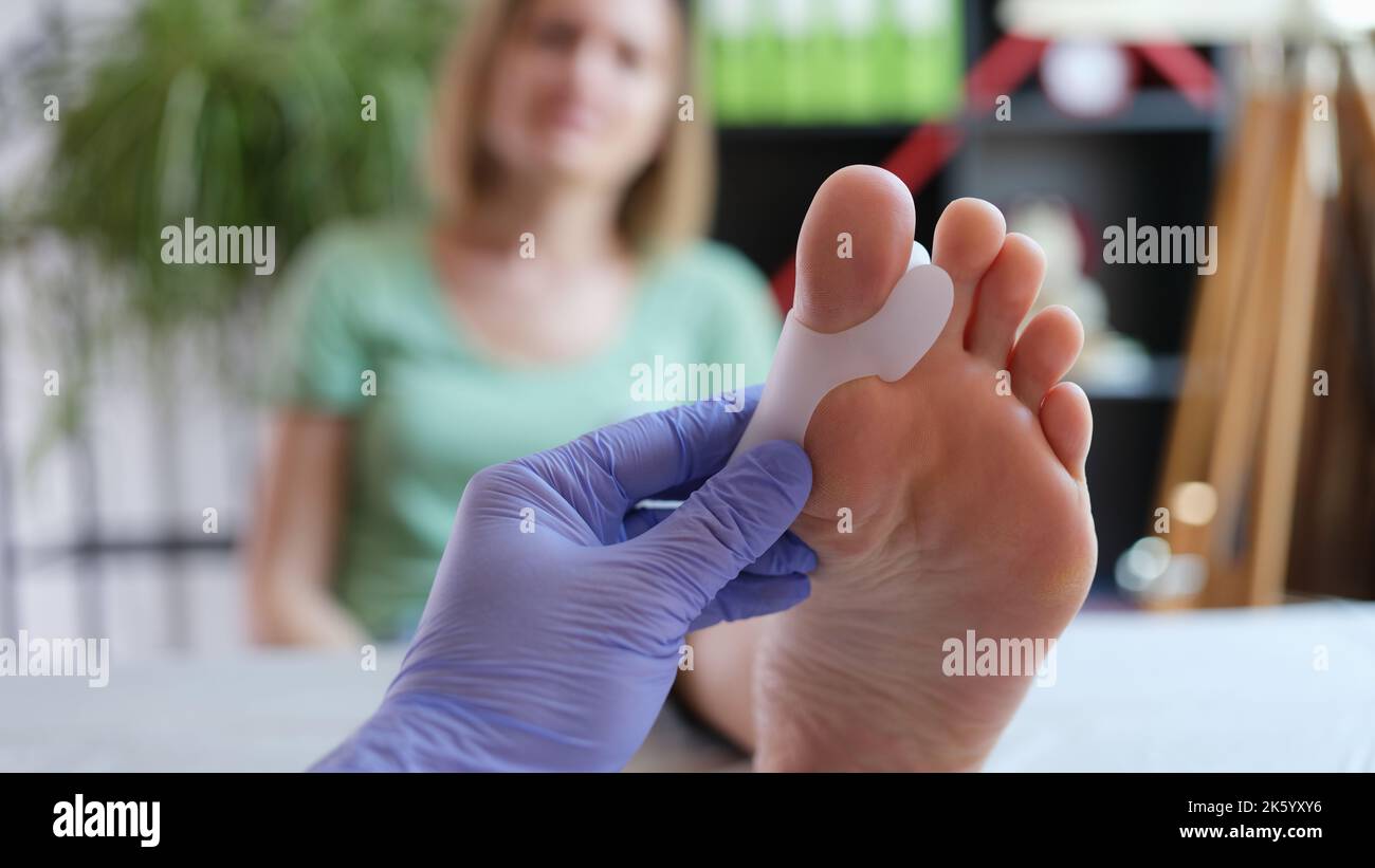 Orthopedist applying brace for hallux valgus for female patient Stock