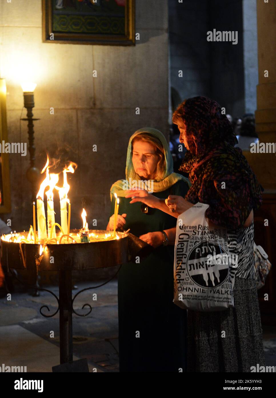 Women lighting candles in the church of the holy sepulchre in the old