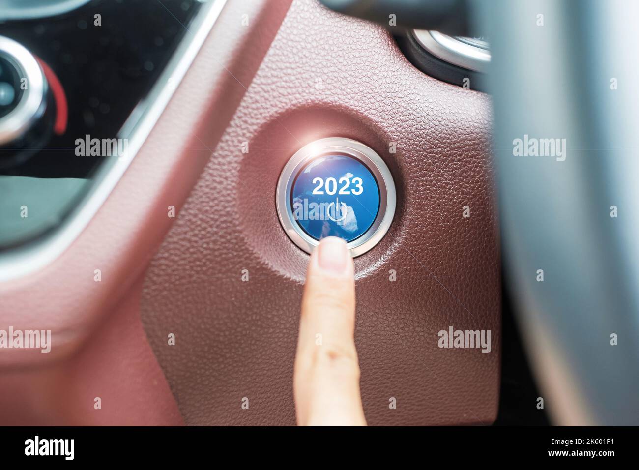 Finger press a car ignition button with 2023 START text inside