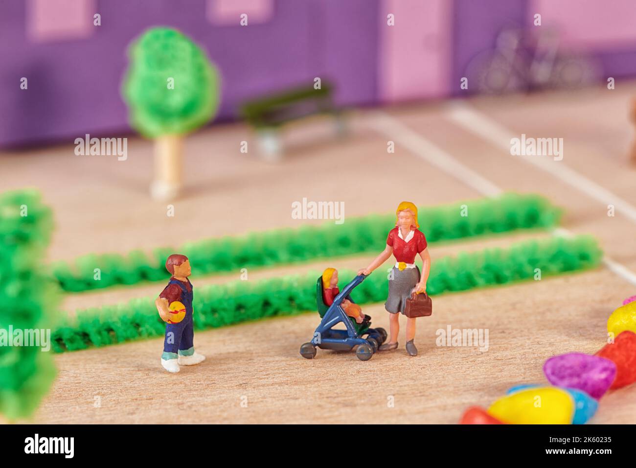 High angle of toy mom holding stroller with toddler near preschool son while walking together against home Stock Photo