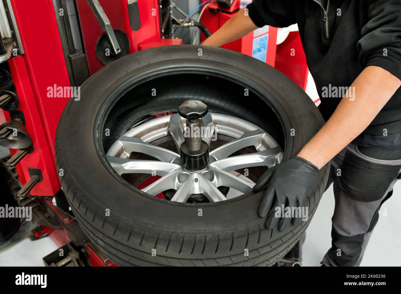 Midsection of male mechanic using machinery to remove tire from wheel at workshop Stock Photo