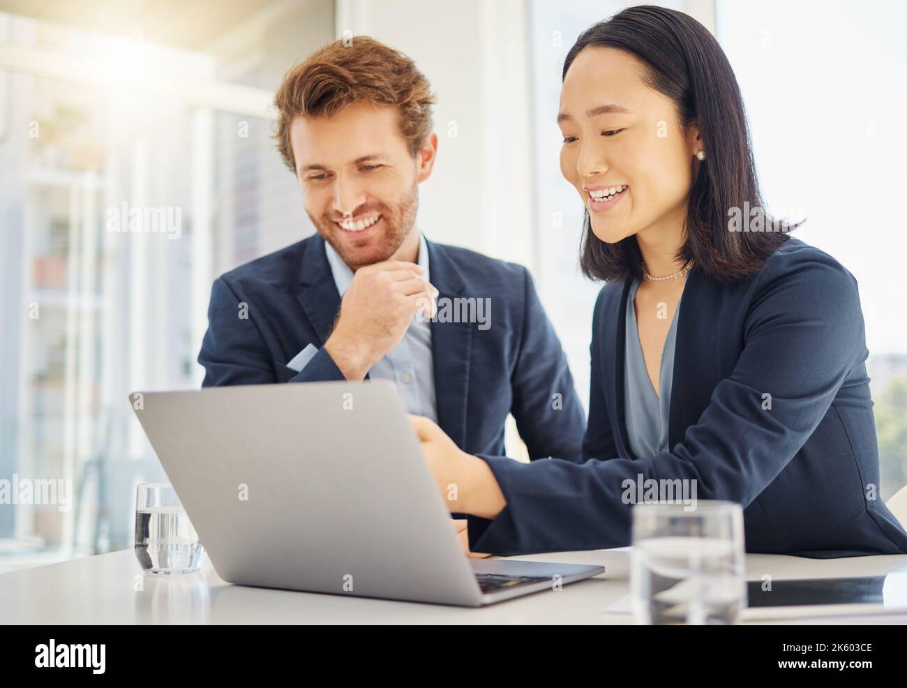 Two happy young diverse colleagues working together on a laptop in an ...