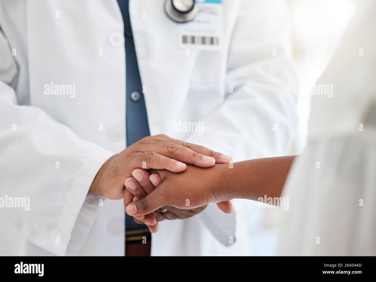 Closeup on hands of doctor being kind to patient. Caring doctor offering patient support during a checkup. Medical specialist holding hands with a Stock Photo