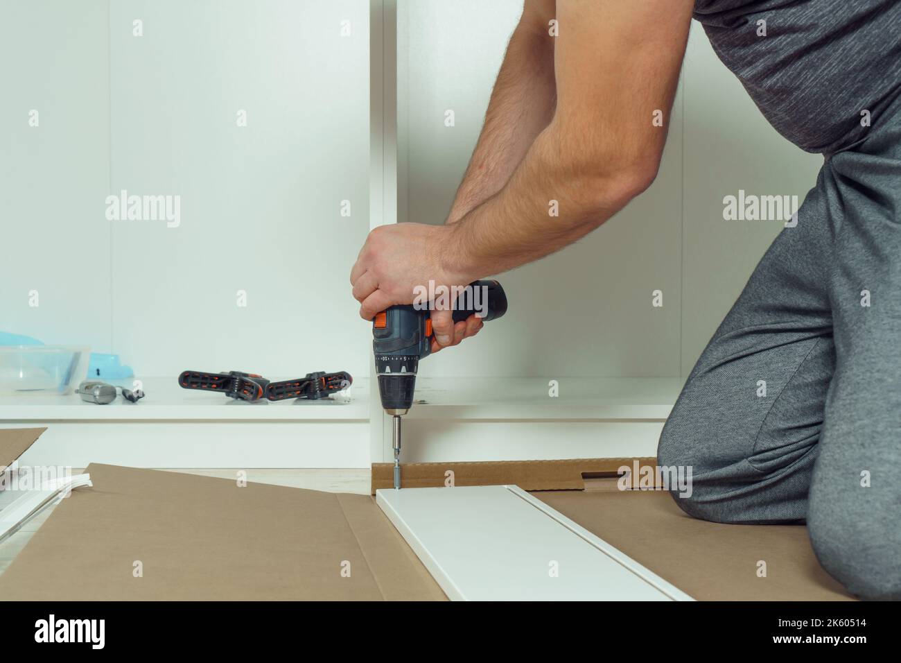Male hands hold cordless electric screwdriver, screw to fix walls of ...