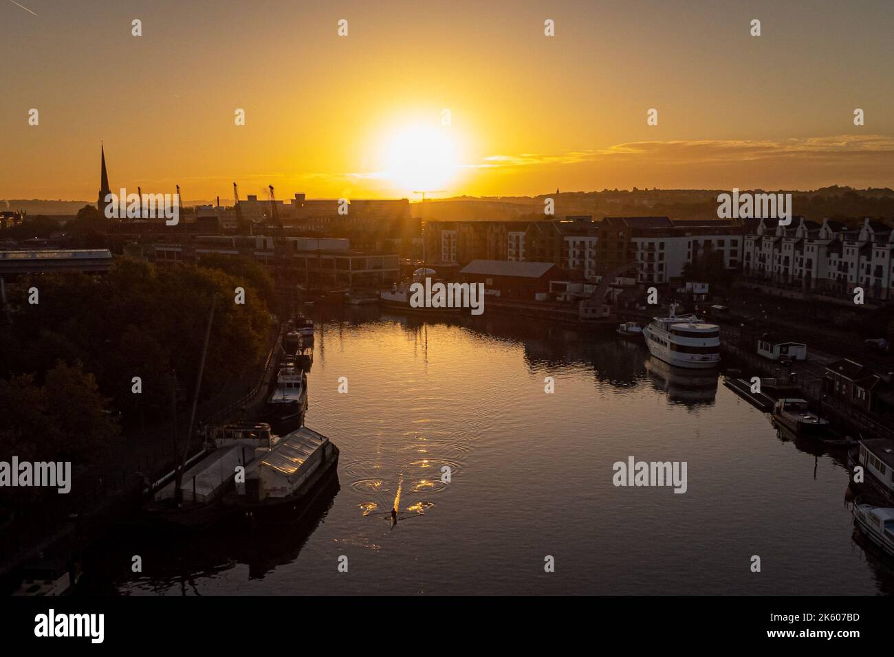 Rowers Pull Along The Water At Bristol Harbourside During A Golden rowers-pull-along-the-water-at-bristol-harbourside-during-a-golden