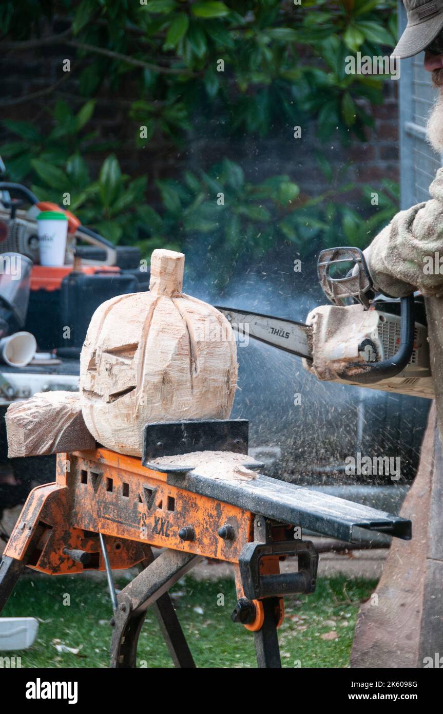 Around the UK - Chain Saw Carving - a wooden pumpkin for Halloween Stock Photo