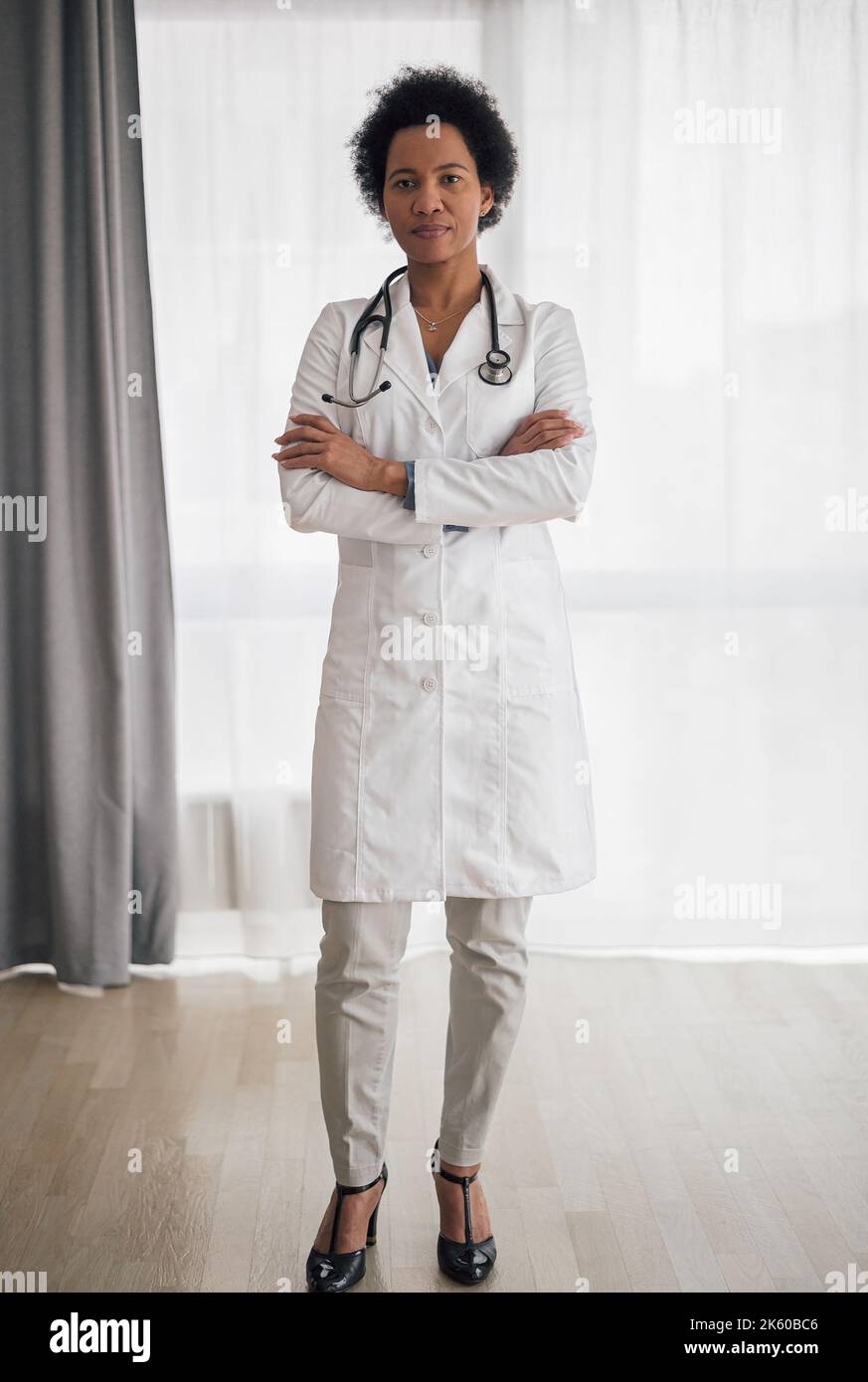 Ambitious africanamerican female doctor in heels, standing crossarmed