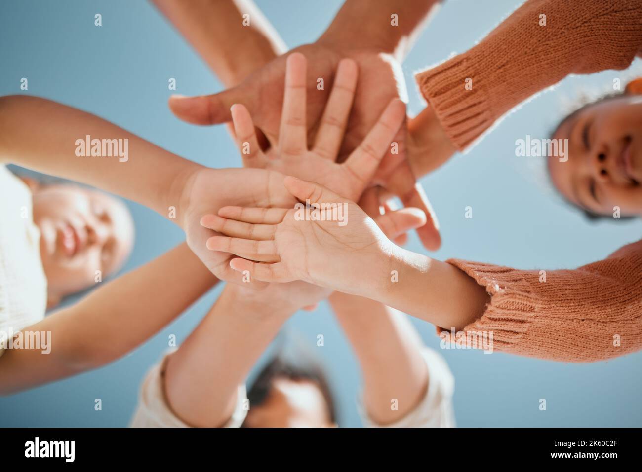 View from below of young mixed race family stacking their hands on top