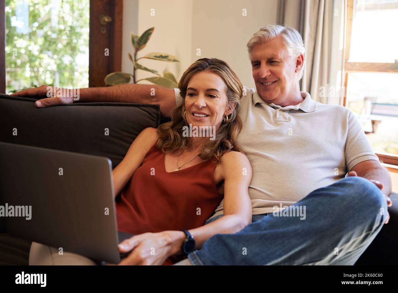 Laptop, couple and retirement with a man and woman streaming an online subscription service on the sofa to relax. Computer, living room and internet Stock Photo