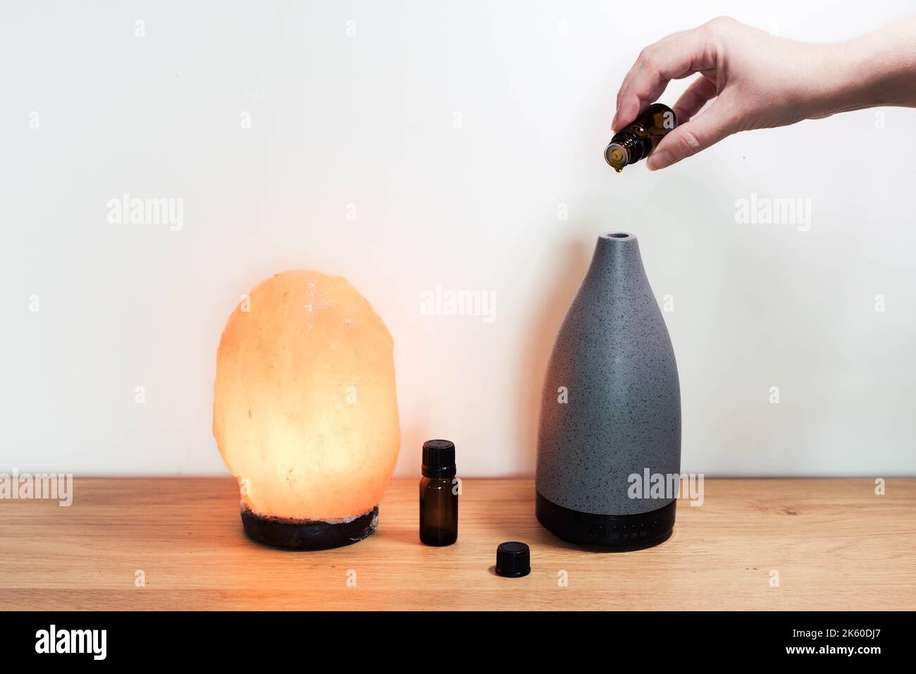 Salt lamp with essential oils and aroma oil diffuser hand pouring in essential oil Stock Photo