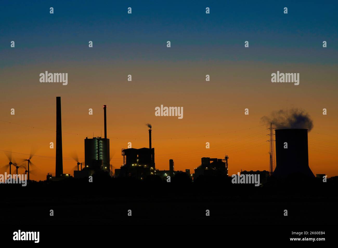 A silhouette of an industrial power plant district with chimneys and ...