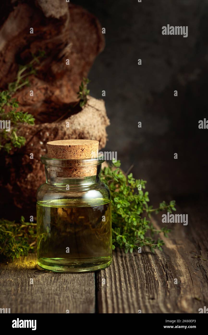 Bottle of thyme essential oil with fresh thyme twigs on an old wooden