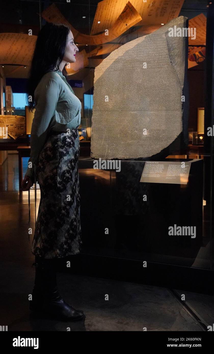 A member of staff observes the Rosetta Stone on display during the  Hieroglyphs: unlocking ancient Egypt exhibition at the British Museum in  London. Picture date: Tuesday October 11, 2022 Stock Photo - Alamy