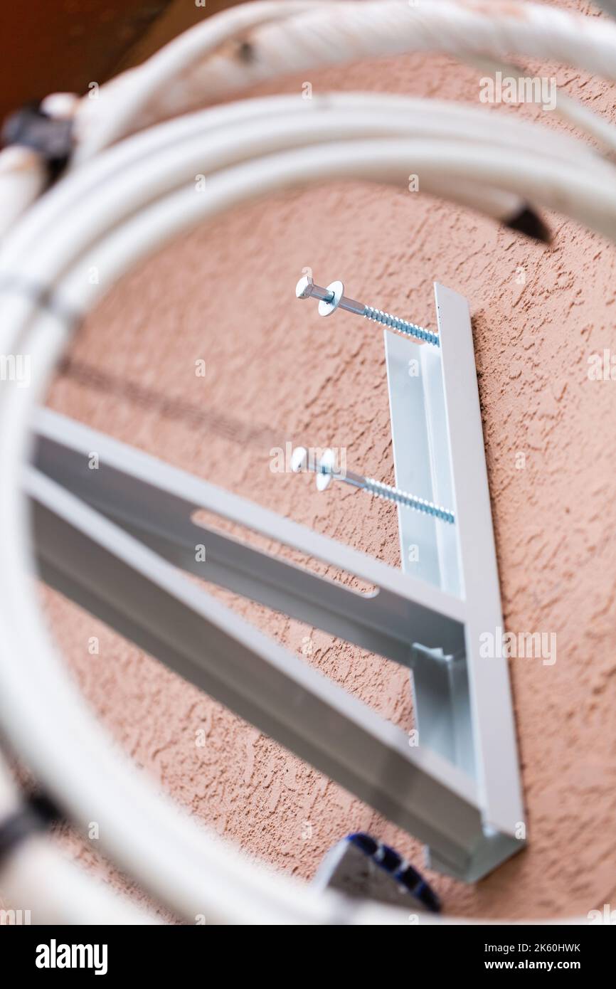 Unscrewed screws on metal holder of wall air conditioner. Close up of