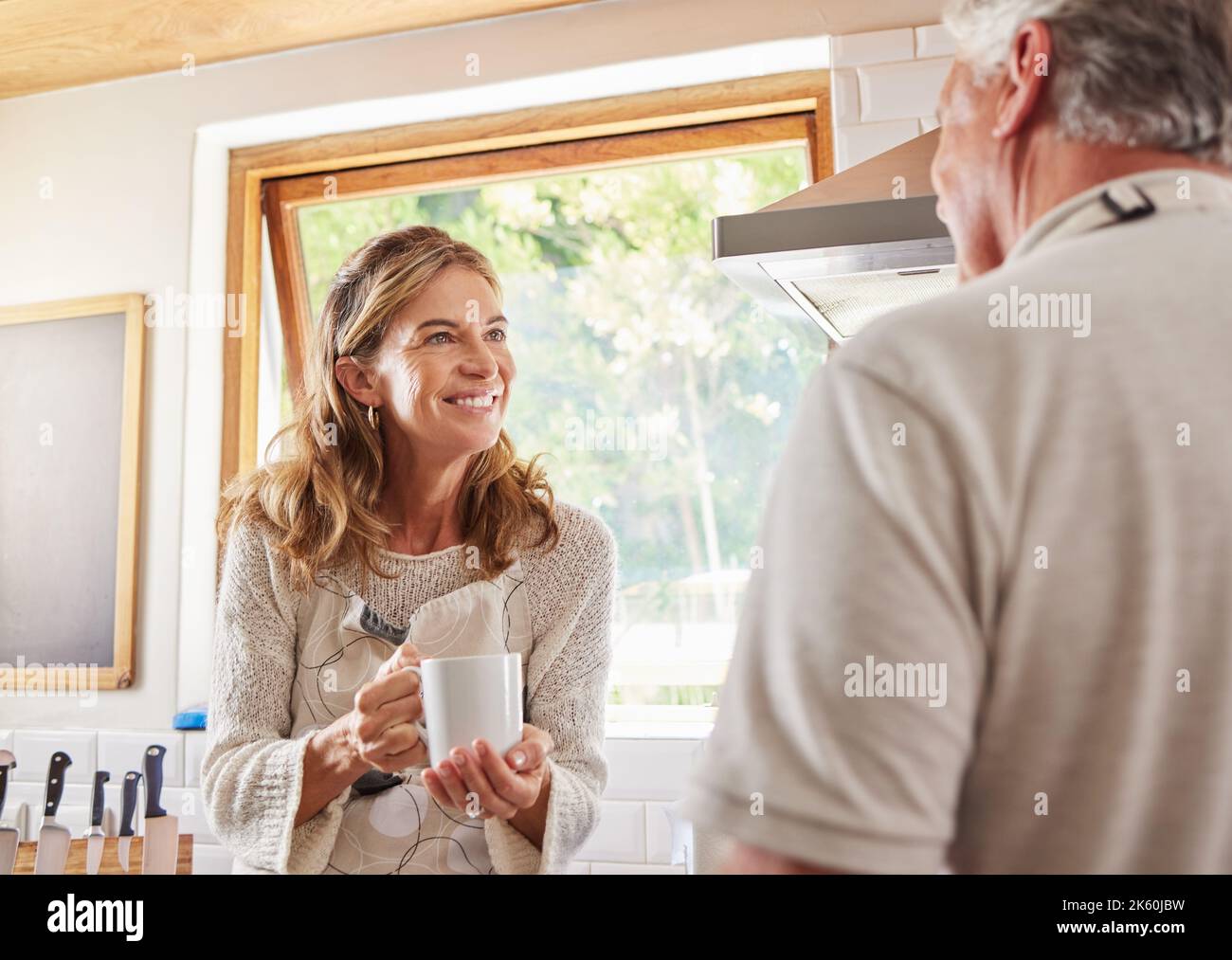 Old couple, coffee and conversation in home kitchen, drinking espresso or caffeine. Retirement, elderly man and woman talking, communication and chat Stock Photo