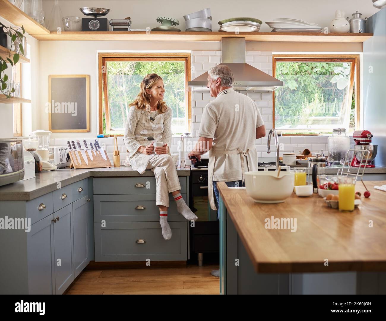 Cooking breakfast together, love and senior couple are happy in their kitchen bonding during retirement. Mature man and woman, communication and relax Stock Photo