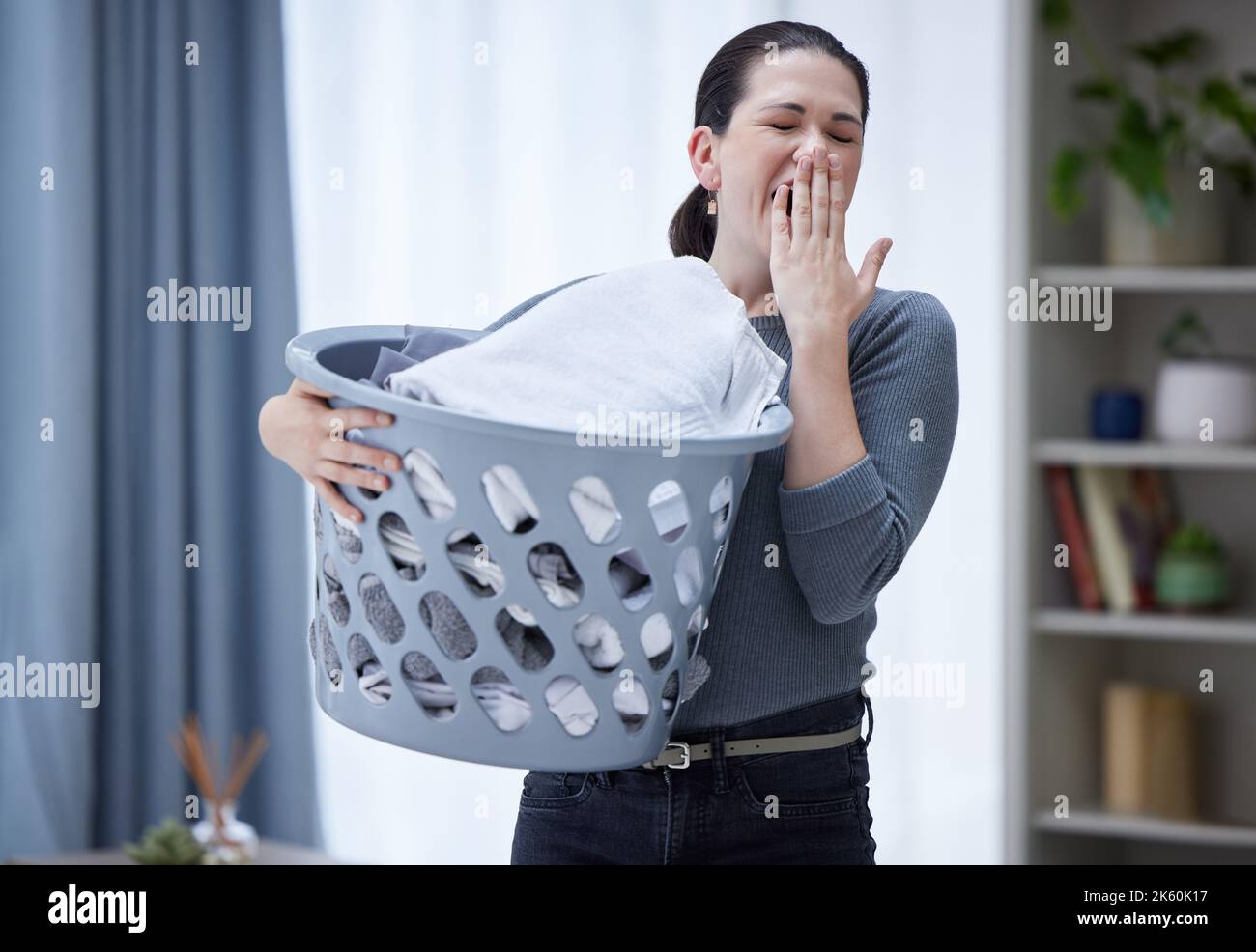 Tired, yawning and woman with laundry basket in home feeling stress