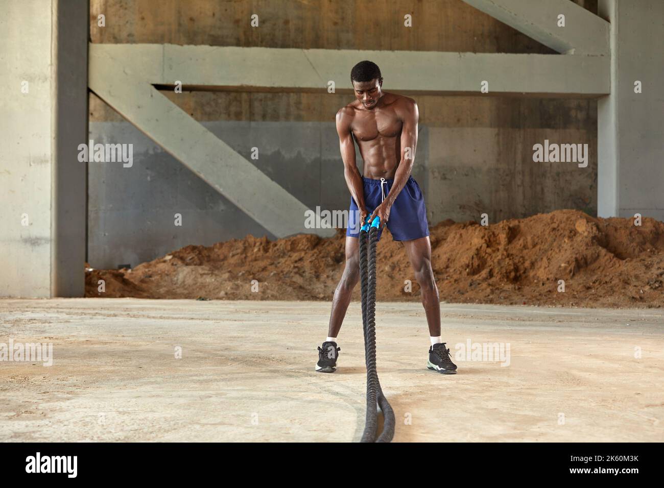 Rope workout. Sport man doing battle ropes exercise outdoor. Black male athlete exercising