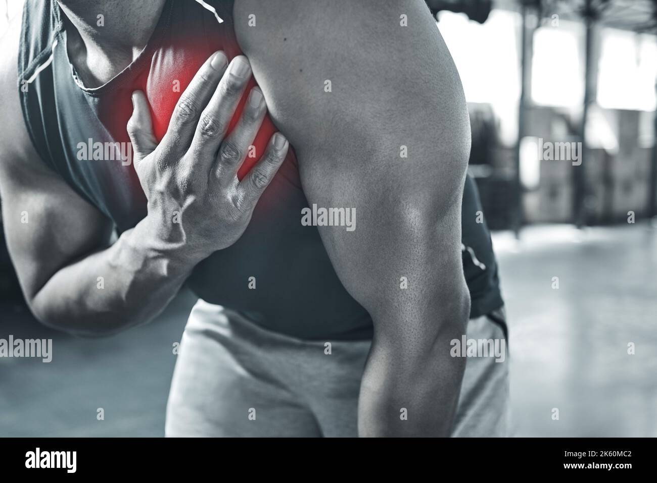 Is this a heart attack Trainer experiencing chest pains at the gym. Hand of a bodybuilder touching his chest in pain. Red CGI spots are used to show Stock Photo