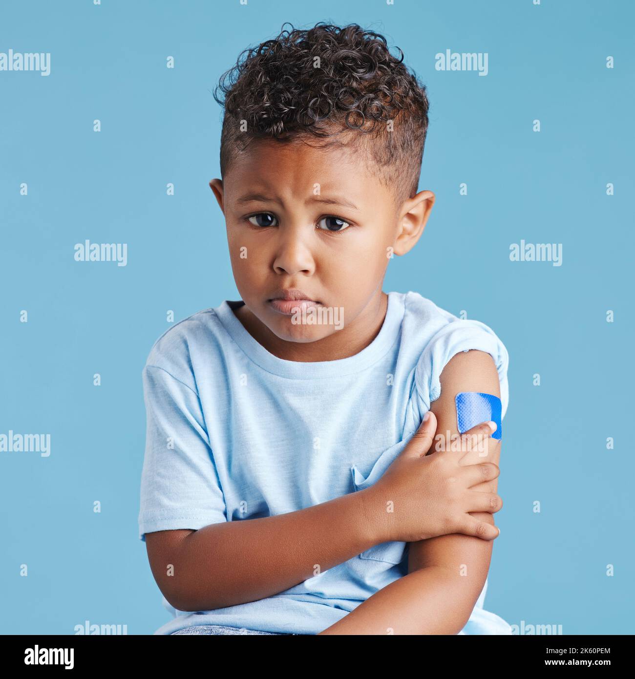 Upset, sad little boy shows vaccinated arm with adhesive bandage after being injected with Covid-19 vaccine, motivates to vaccinate against Stock Photo