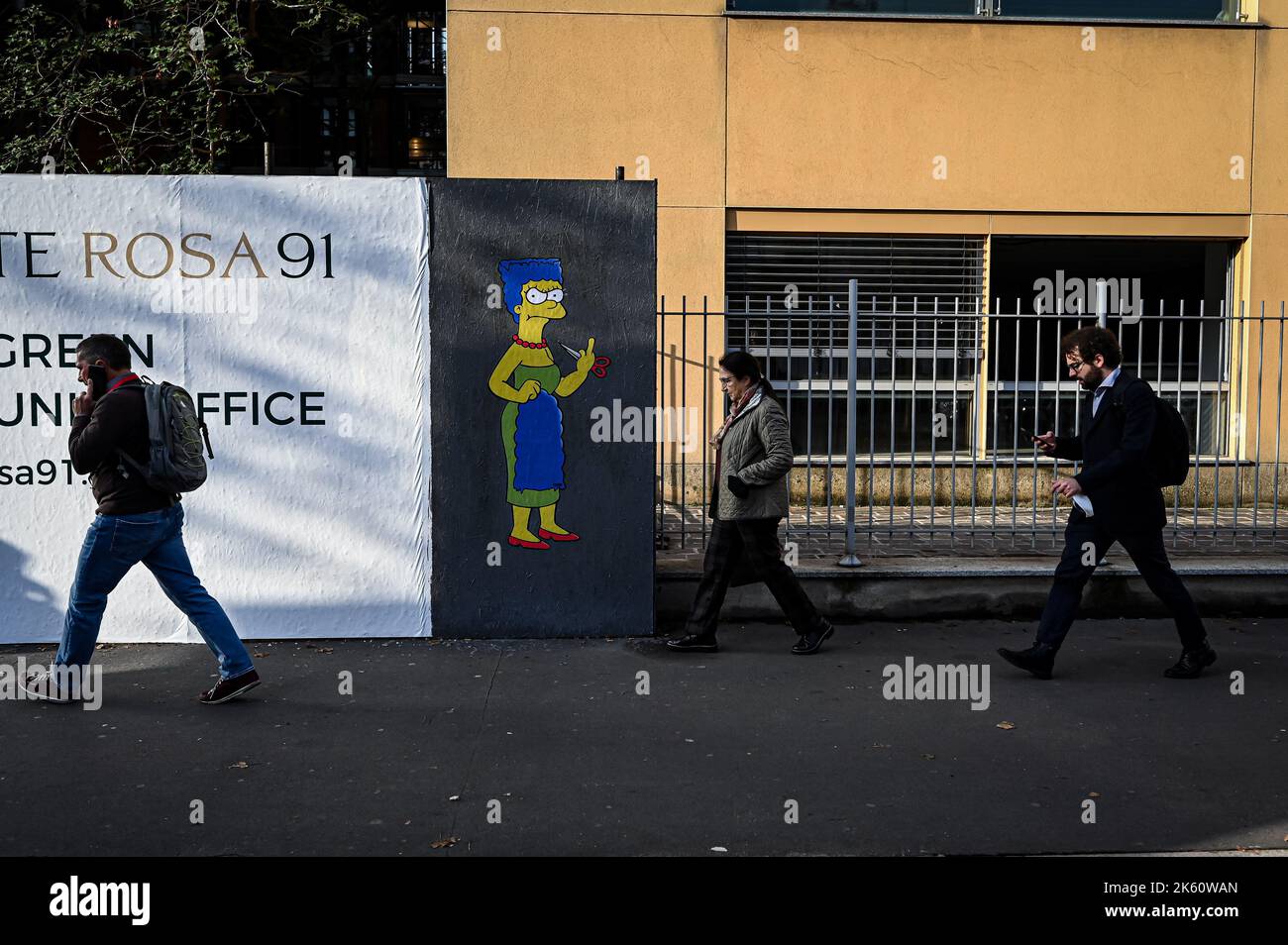 Milan, Italy on October 11, 2022, People walk past a mural entitled ‘The Cut 2’ by street artist aleXsandro Palombo depicting The Simpsons' character Marge Simpson cutting her hair and giving the middle finger in solidarity with the women of Iran in front of the Iranian Consulate in Milan, Italy on October 11, 2022. A first version of a similar mural, entitled 'The Cut' appeared on October 5 at the same location and was later on removed. Credit: Piero Cruciatti/Alamy Live News Credit: Piero Cruciatti/Alamy Live News Stock Photo