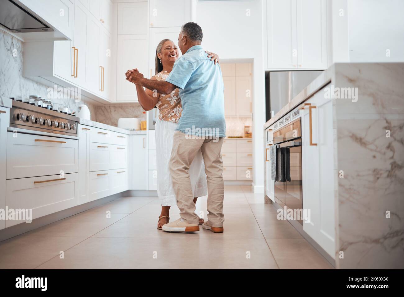 Couple, elderly and dance in kitchen for love, romance and happy together while home in retirement. Senior, man and woman do fun dancing in house for Stock Photo