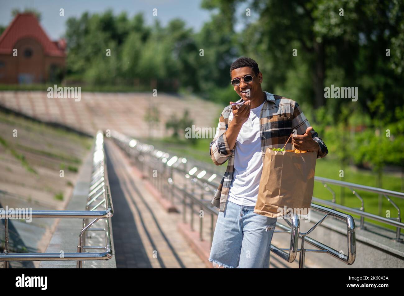 Young man in plaid shirt recording a voice message Stock Photo