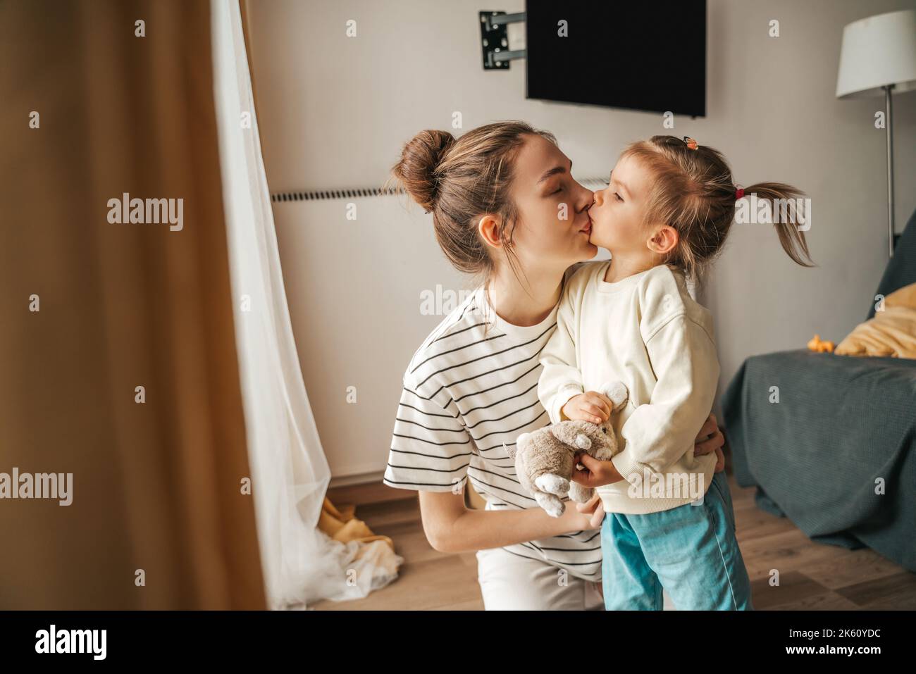 Affectionate mother giving a kiss to her daughter Stock Photo