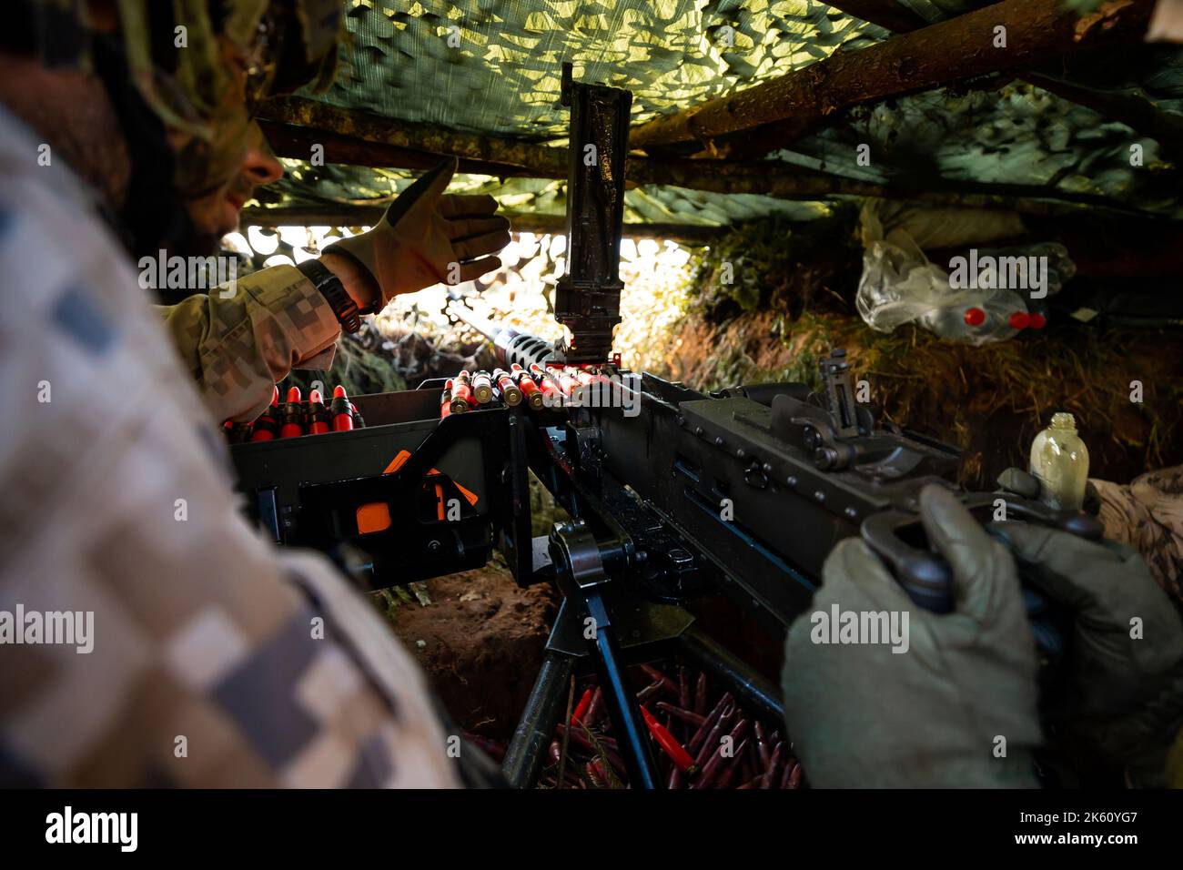 Close-up soldiers firing a 50 Cal Machine gun with spent brass around it Stock Photo