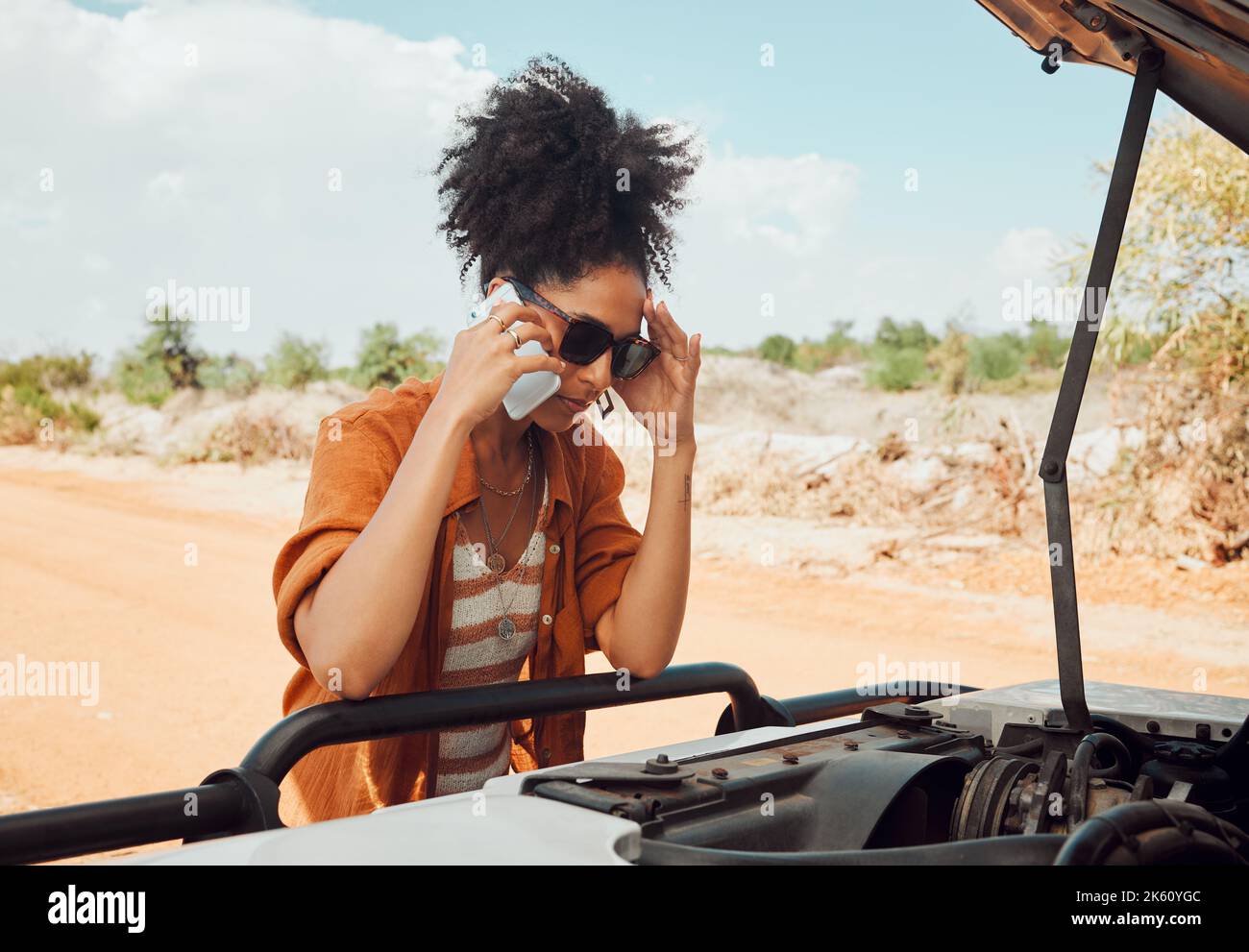 Worried woman, phone call and engine problems speaking to engineer or mechanic on a desert road in nature. Stressed black female calling roadside Stock Photo