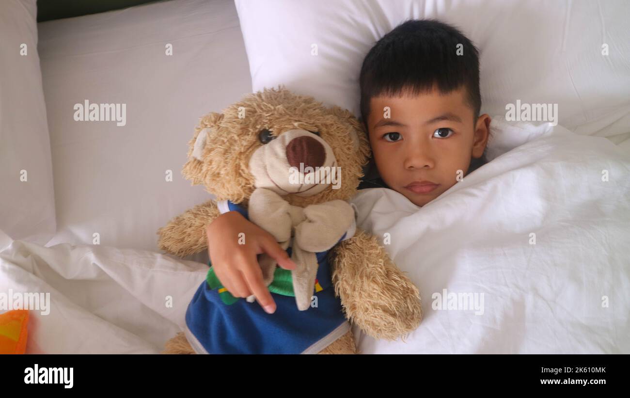 an adorable boy with a teddy bear on a bed Stock Photo - Alamy