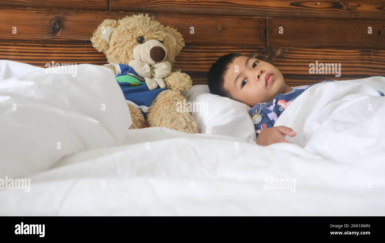 an adorable boy with a teddy bear on a bed Stock Photo - Alamy