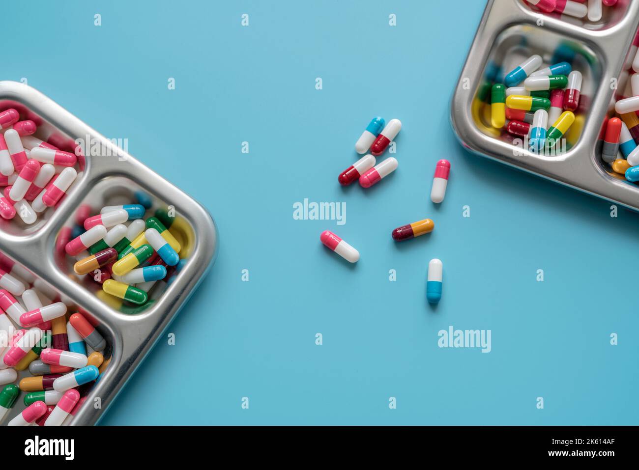 Multicolored capsule pills in stainless steel tray and on blue
