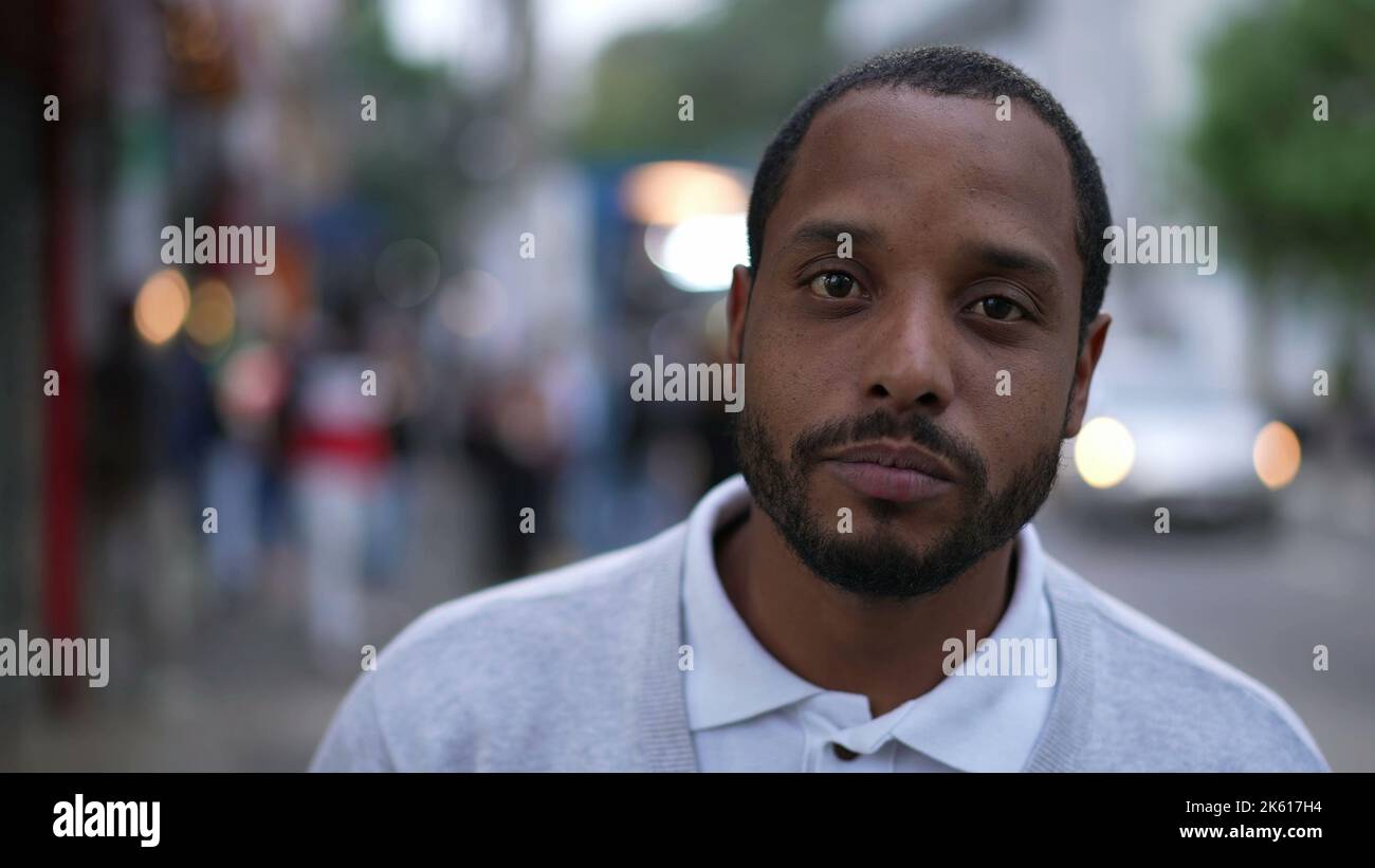 Portrait of a black man standing in street looking at camera. Closeup ...