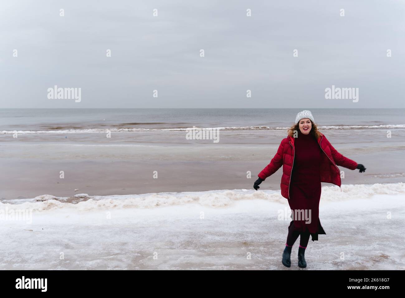 Smiling woman runs along the seashore in winter near Baltic Sea in Jūrmala, Latvia Stock Photo