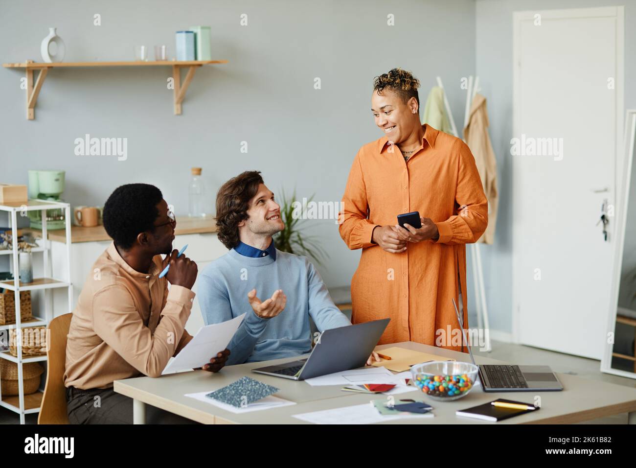Portrait of three smiling business people discussing project development in meeting and enjoying work at small company office Stock Photo