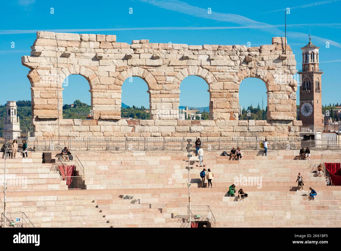 Verona, view in summer of the remaining four arches of the outer wall of the Roman Arena with tourists seated inside the amphitheater, Verona, Italy Stock Photo